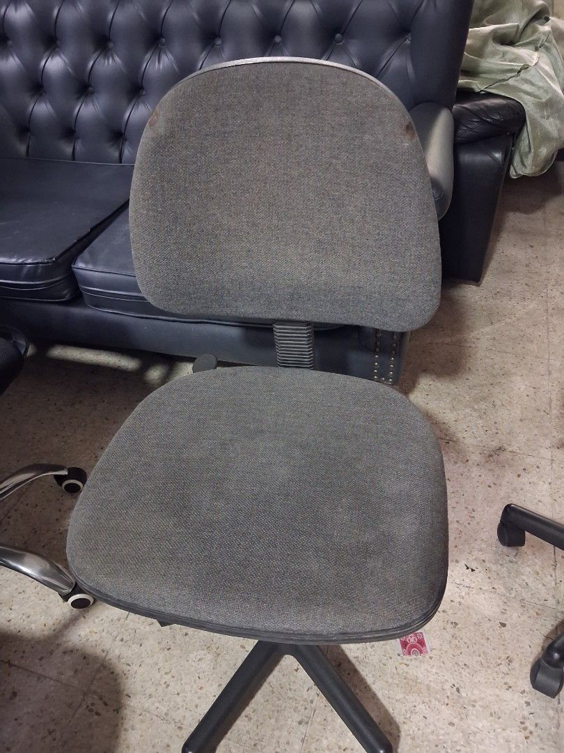 Grey rolling office chair with wheels (Category: Office Furniture & Fixtures) located in Quezon City. Submitted by ssvcn (Listing ID 1466602767, Image 3). Description: - Color: Grey - Material: Fabric upholstery on seat and backrest with a sturdy metal star base - Mobility: Rolling casters for easy movement - Adjustability: Height-adjustable gas lift mechanism - Condition: Fully functional and sturdy, with minor stains visible on the backrest fab