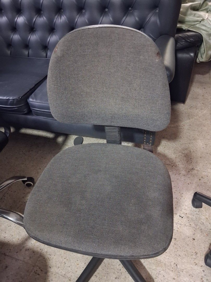 Grey rolling office chair with wheels (Category: Office Furniture & Fixtures) located in Quezon City. Submitted by ssvcn (Listing ID 1466602767, Image 2). Description: - Color: Grey - Material: Fabric upholstery on seat and backrest with a sturdy metal star base - Mobility: Rolling casters for easy movement - Adjustability: Height-adjustable gas lift mechanism - Condition: Fully functional and sturdy, with minor stains visible on the backrest fab