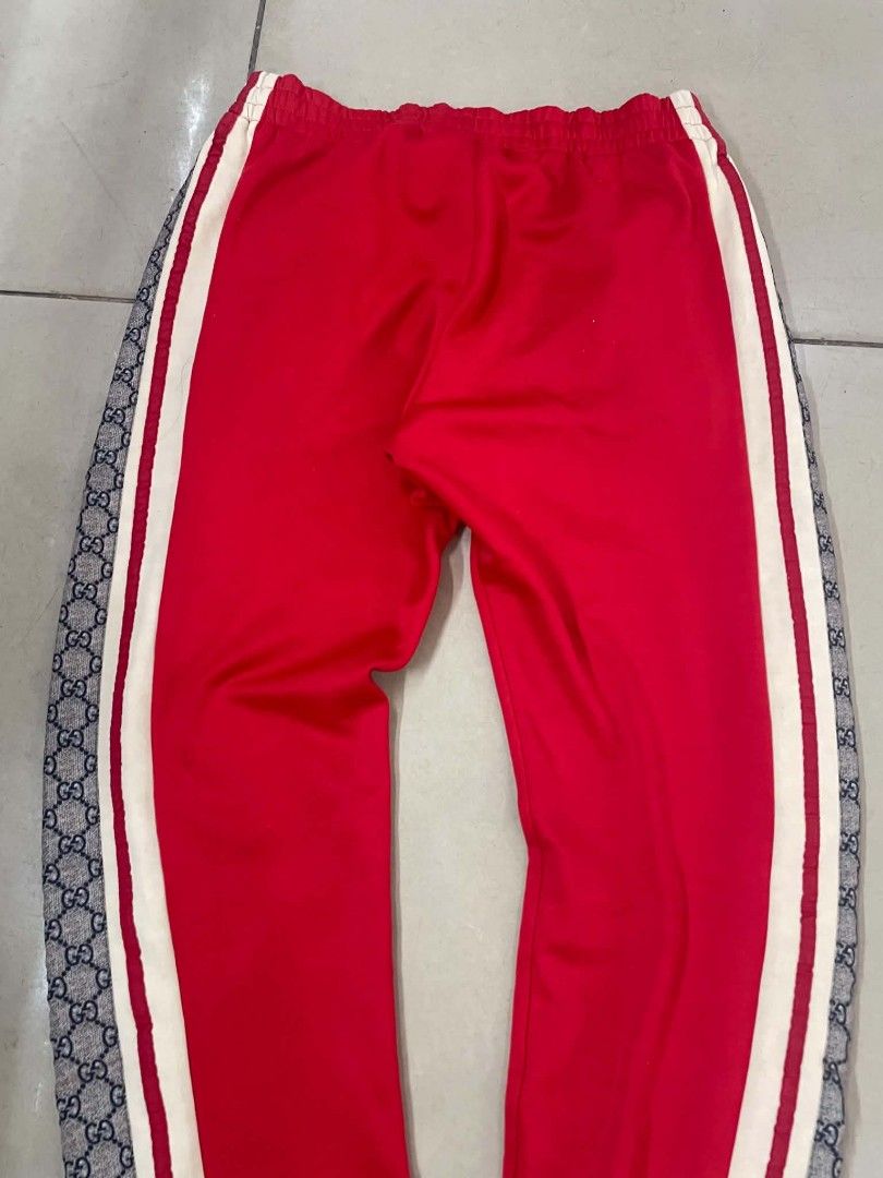 Gucci GG Supreme Side Stripe Red Jogging Pants (Category: Joggers) located in Cainta. Submitted by riszizlux (Listing ID 1466671653, Image 3). Description: - Brand: Gucci - Color: Red with cream taping and GG Supreme canvas side stripes - Size: Medium (M) tag attached - Material: Premium cotton blend, Made in Italy - Features: Elastic waistband with adjustable drawstring, secure zippered front pockets, and ribbed ankle cuffs - Condition: Excellen