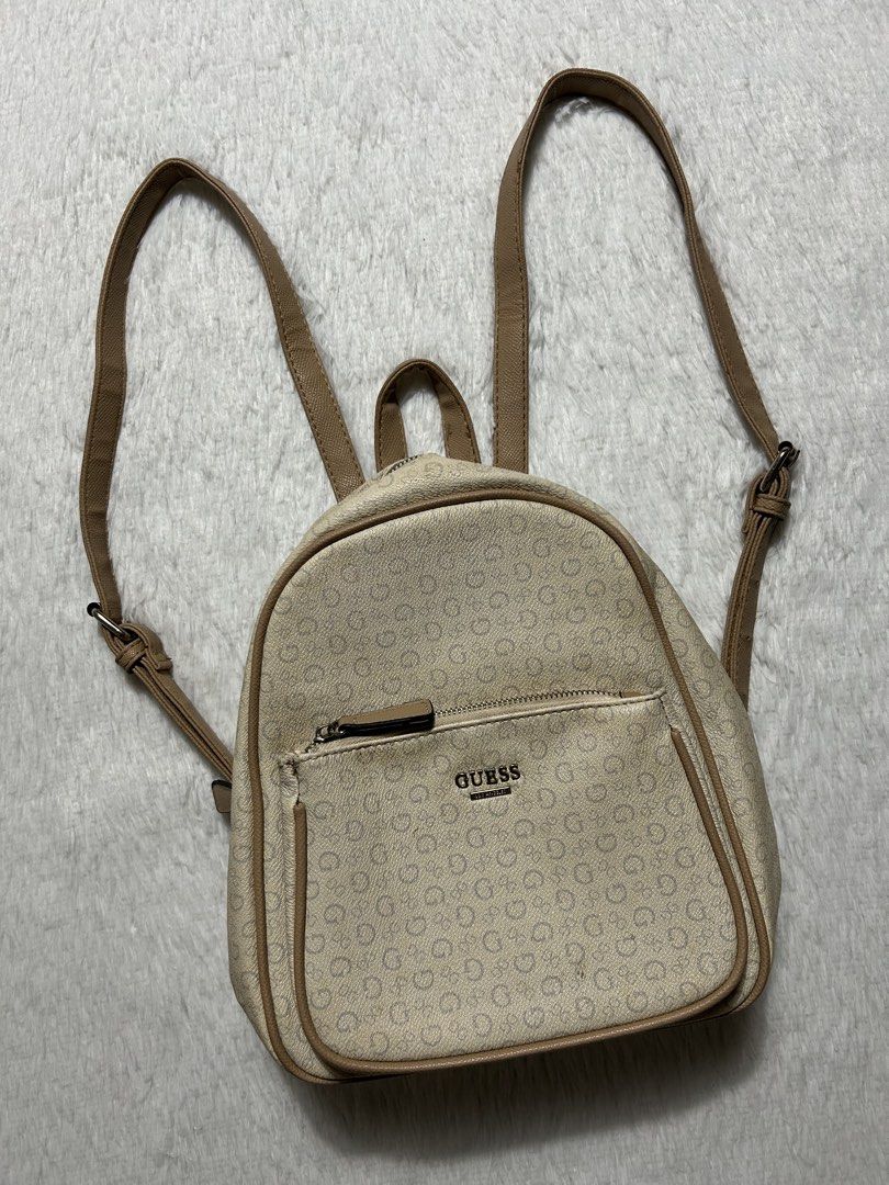 Guess Cream and Beige Monogram Mini Backpack (Category: Backpacks) located in Quezon City. Submitted by commonwealthpickerph (Listing ID 1466617375, Image 2). Description: Guess Cream and Beige Monogram Mini Backpack 10.5 width // 11 length - Color: Cream and beige with all-over logo print - Design: Mini backpack with zip-around closure and top handle - Straps: Adjustable brown straps for comfort - Pockets: Front zip pocket, inside zippered back 