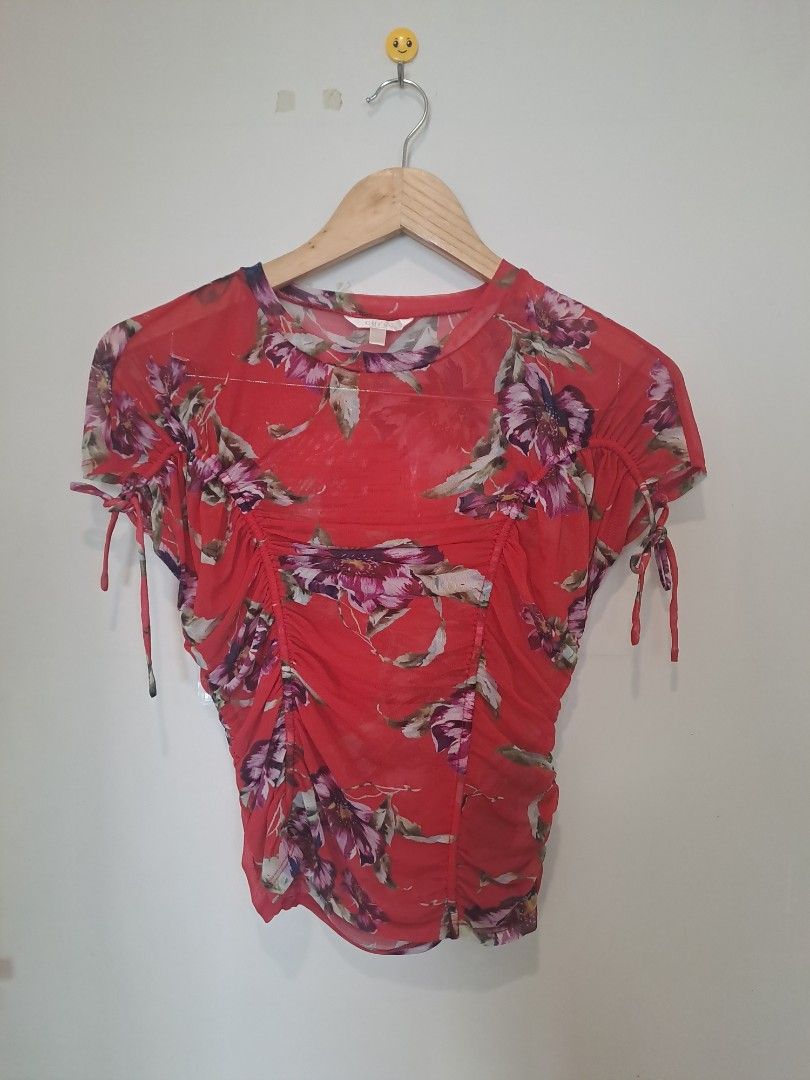 Guess floral mesh (Category: Blouses) located in Manila. Submitted by joanbalde39643 (Listing ID 1466663391, Image 1). Description: This piece is a GUESS vibrant red floral mesh ruched top featuring short cap sleeves with functional drawstring tie details. It showcases an all-over tropical botanical pattern highlighted by purple and magenta hibiscus flowers and is constructed from a lightweight, semi-sheer mesh fabric with central ruched body sha