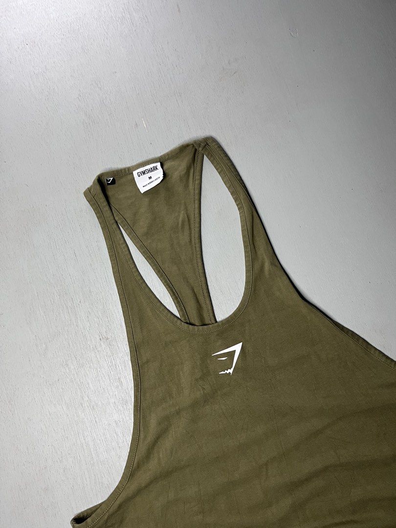 Gymshark Olive Green Stringer Tank Top Size M (Category: Activewear) located in Catbalogan. Submitted by yellfindss (Listing ID 1466753119, Image 2). Description: - Brand: Gymshark 18/29 - Item: Stringer Tank Top - Color: Olive Green - Size: Medium - Material: 95% Cotton, 5% Elastane - Style Code: GMSR3250-OGN - Features: Classic racerback, white chest logo - Condition: Clean fabric with clear collar tag branding.