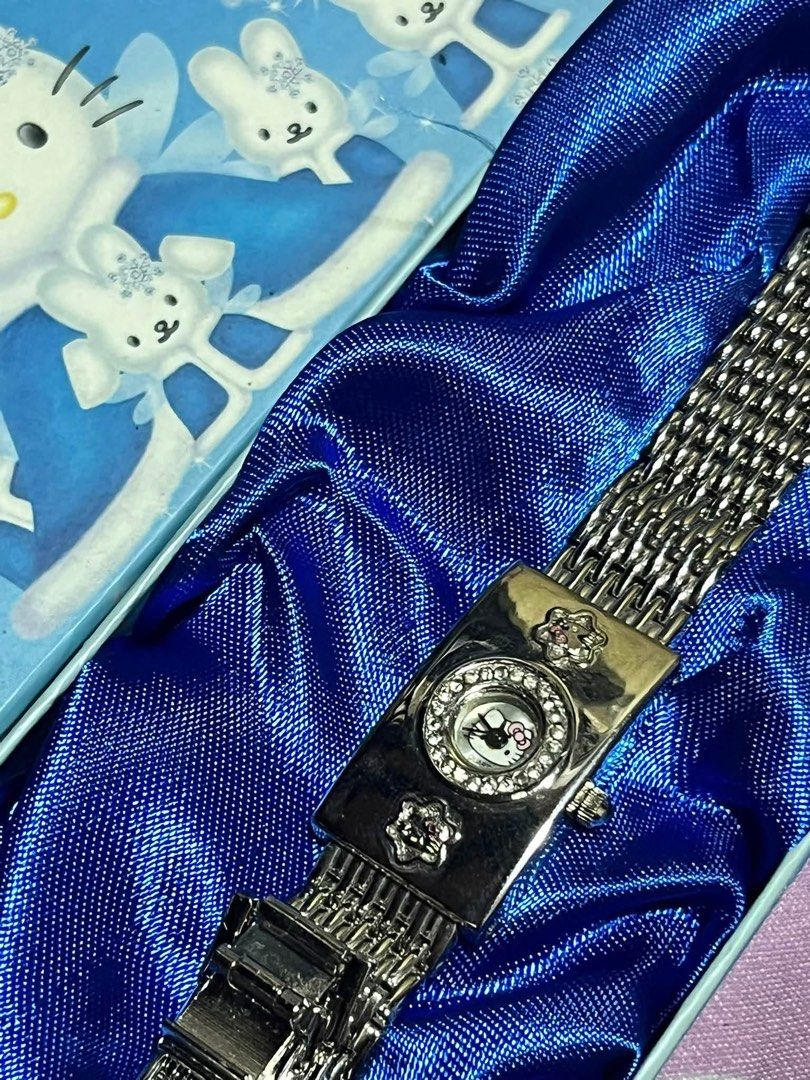 Hello Kitty Rhinestone Analog Watch with Gift Box (Category: Women's Watches) located in Manila. Submitted by janetecson05 (Listing ID 1466586761, Image 2). Description: - Authentic Kitty themed analog watch in a sleek silver tone - Sparkling rhinestone bezel and cute Kitty watch face graphic - Charming decorative flower accents on the rectangular case - Adjustable metal mesh strap with a secure clasp closure - Includes original collectible blue 