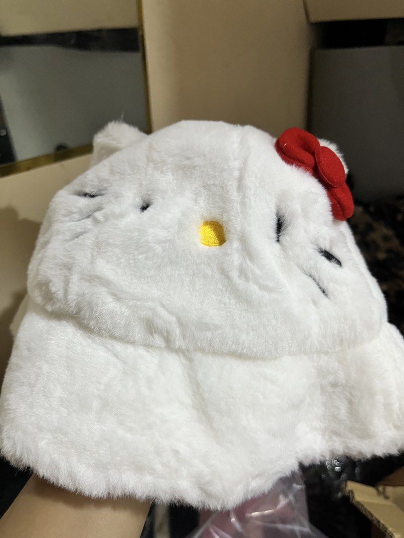 Hello Kitty white fluffy bucket hat with red bow (Category: Hats & Beanies) located in Manila. Submitted by janetecson05 (Listing ID 1466648803, Image 1). Description: - Condition: Brand new, unworn with tag attached - Material: Soft plush faux fur all over, fully lined interior - Design: White bucket hat with Kitty character details - Accents: Cute bright red plush bow on the side - Branding: Red embroidered Kitty text on the brim.