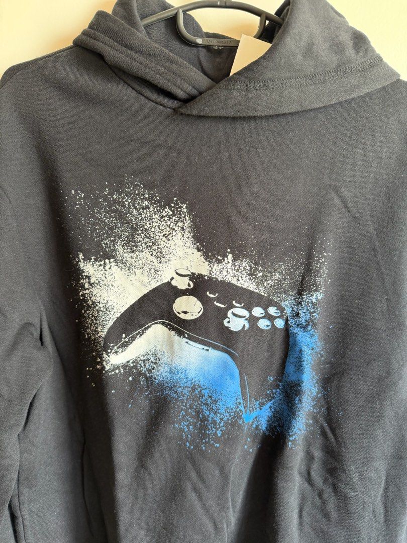 H&M Black Gaming Controller Graphic Hoodie (Category: Hoodies) located in Quezon City. Submitted by bubspreloved (Listing ID 1466719535, Image 2). Description: - Condition: Brand new with tags (BNWT), never worn - Design: Black hoodie with blue and white video game controller graphic - Fit & Comfort: Regular fit, soft fabric, pullover style with hood - Size: US 16/18 or UK 12-14Y.