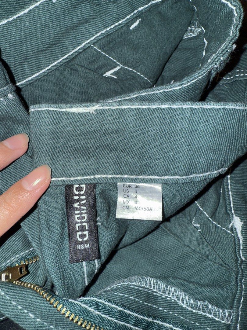 H&M Divided Green Cargo Pants Size US 4 (Category: Jeans) located in Angeles City. Submitted by kkucart (Listing ID 1466691369, Image 2). Description: - Brand: H&M Divided - Size: EUR 36 / US 4 / CA 4 / MX 4 - Color: Dark forest green with contrast white stitching - Fit: Mid-rise with a relaxed straight leg cut - Details: Zip fly with button closure and functional side utility pockets - Condition: Worn 1-2 times, still looks great - Note: Refer t