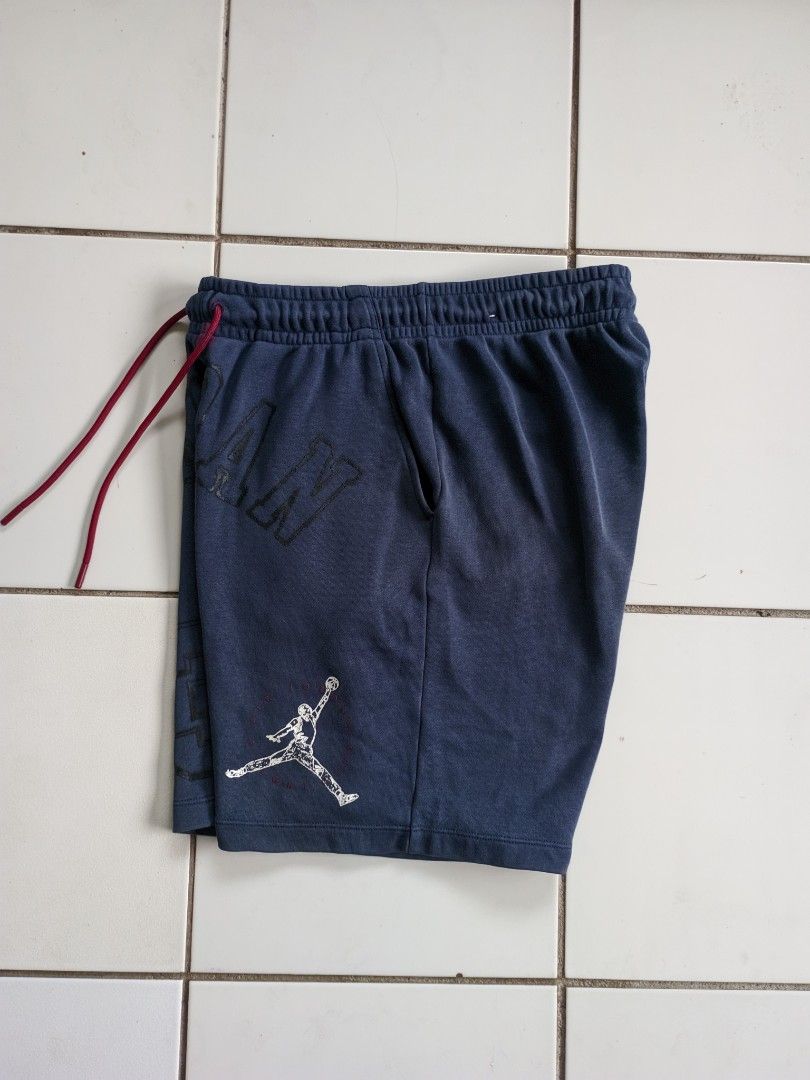 Jordan Essentials Men's Loopback Fleece / Knit Shorts (Category: Shorts) located in Iriga City. Submitted by cxvgarments (Listing ID 1466637242, Image 1). Description: • Color: Navy blue with red drawstrings and white/black graphics. • Details: Features the debossed "JORDAN" arch lettering across the front waistband area, a large "23" graphic with the classic Michael Jordan silhouette on the left leg, and the Jumpman logo on the right leg. • Mate