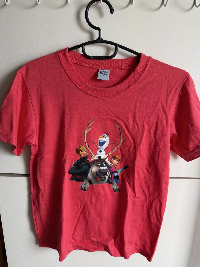 Junior Basic Frozen Graphic T-Shirt Red Size 16 (Category: Babies & Kids Fashion) located in Quezon City. Submitted by bubspreloved (Listing ID 1466725867, Image 1). Description: - Design: Features Frozen characters Olaf, Sven, Anna, and Kristoff on the front - Color: Bright red with a solid plain back - Material: Soft and comfortable cotton - Style: Short sleeves with classic crew neck - Size: Size 16 (Junior Basic brand label) - Condition: Grea