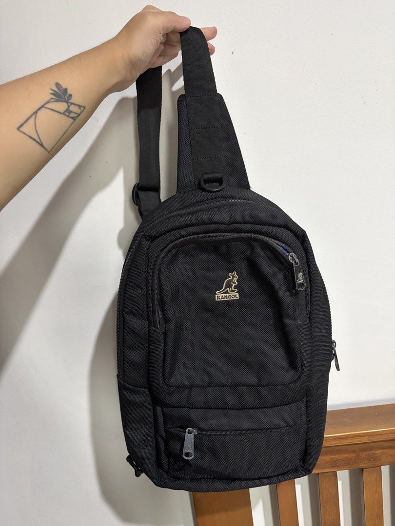 Kangol Black Sling Bag Crossbody Backpack (Category: Sling Bags) located in Marikina City. Submitted by kim_sanaaa (Listing ID 1466772150, Image 1). Description: - Authentic Kangol sling bag in classic black - Vibrant blue interior lining - Multiple exterior and interior zippered pockets for easy organization - Adjustable single shoulder strap for comfort - Premium branded zippers and iconic embroidered kangaroo logo Issues: Lost 1 main zipper (s