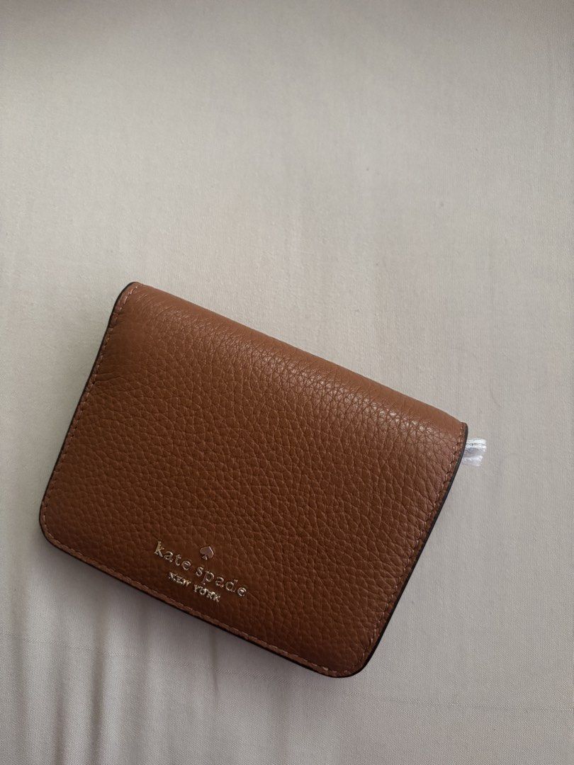 Kate Spade Lena Small Bifold Wallet (Category: Wallets & Card holders) located in Malabon City. Submitted by jesabibi (Listing ID 1466603160, Image 1). Description: - Brand: Kate Spade - Style: Small slim bifold wallet (Style KH788) - Color: Warm Ginger Brown (200) - Material: Premium pebbled leather with gold-tone hardware - Features: Multiple card slots, bill compartment, and secure snap closure - Condition: Brand new, unused, and still in orig