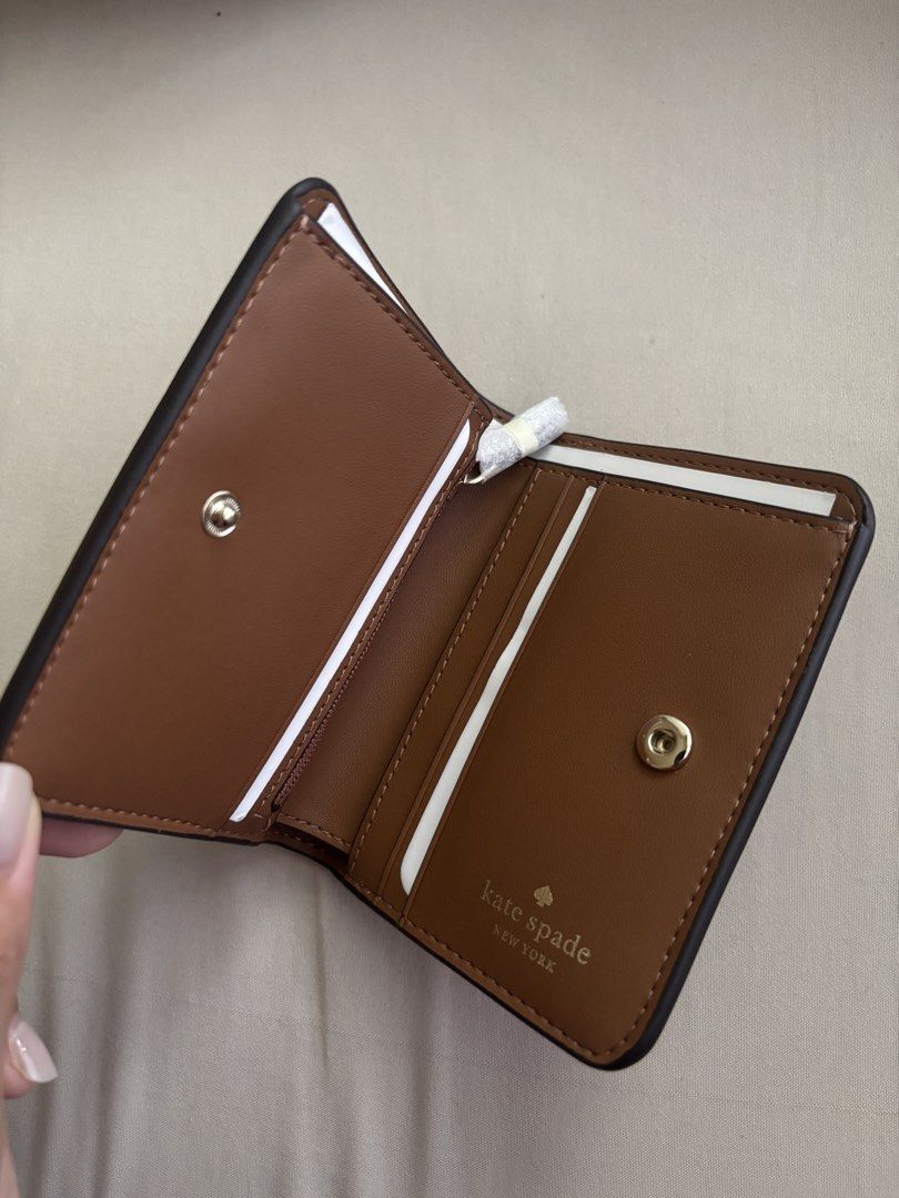 Kate Spade Lena Small Bifold Wallet (Category: Wallets & Card holders) located in Malabon City. Submitted by jesabibi (Listing ID 1466603160, Image 2). Description: - Brand: Kate Spade - Style: Small slim bifold wallet (Style KH788) - Color: Warm Ginger Brown (200) - Material: Premium pebbled leather with gold-tone hardware - Features: Multiple card slots, bill compartment, and secure snap closure - Condition: Brand new, unused, and still in orig