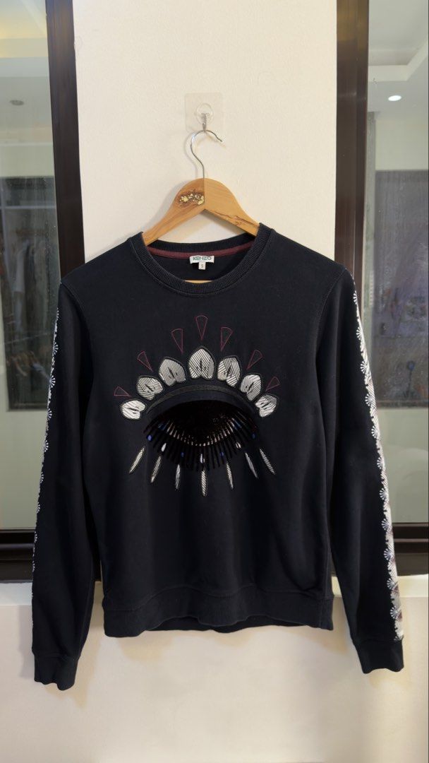 Kenzo Paris Black Eye Sweatshirt Size S (Category: Coats, Jackets and Outerwear) located in Paranaque City. Submitted by mykapoynton (Listing ID 1466769499, Image 2). Description: Kenzo Paris Black Eye Sweatshirt Size S - Color: Black with patterned sleeve stripes - Design: Iconic embroidered eye motif on chest - Size: Small (Regular fit) - Material: Premium cotton with soft fleece backing - Origin: Made in Portugal - Details: Ribbed crewneck wit
