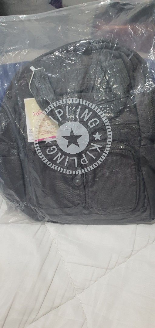 Kipling Grey Backpack with Front Pockets (Category: Backpacks) located in Paranaque City. Submitted by personal_preloved40 (Listing ID 1466656411, Image 1). Description: - Brand: Kipling - Color: Dark grey with grey and white striped interior lining - Condition: Brand new with original tags, kept in protective plastic - Features: Dual zippered front pockets, top grab handle, and adjustable back straps - Interior: Includes convenient slip compartm