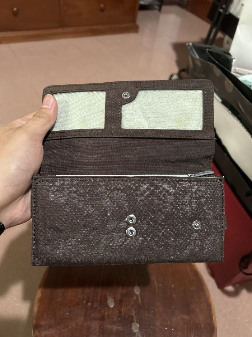 Kipling Long Wallet Dark Grey Textured (Category: Wallets & Card holders) located in Alitagtag. Submitted by patrickvillanueva (Listing ID 1466628867, Image 3). Description: Kipling long wallet in a dark grey textured fabric. Snap button closure on the front flap. Inside has multiple card slots, clear ID windows, bill compartments, and a zippered coin pocket. Shows some yellowing inside the clear ID slots from age and storage. Clean fabric exteri