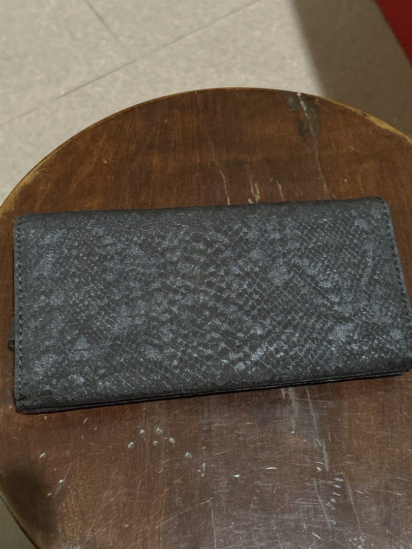 Kipling Long Wallet Dark Grey Textured (Category: Wallets & Card holders) located in Alitagtag. Submitted by patrickvillanueva (Listing ID 1466628867, Image 2). Description: Kipling long wallet in a dark grey textured fabric. Snap button closure on the front flap. Inside has multiple card slots, clear ID windows, bill compartments, and a zippered coin pocket. Shows some yellowing inside the clear ID slots from age and storage. Clean fabric exteri