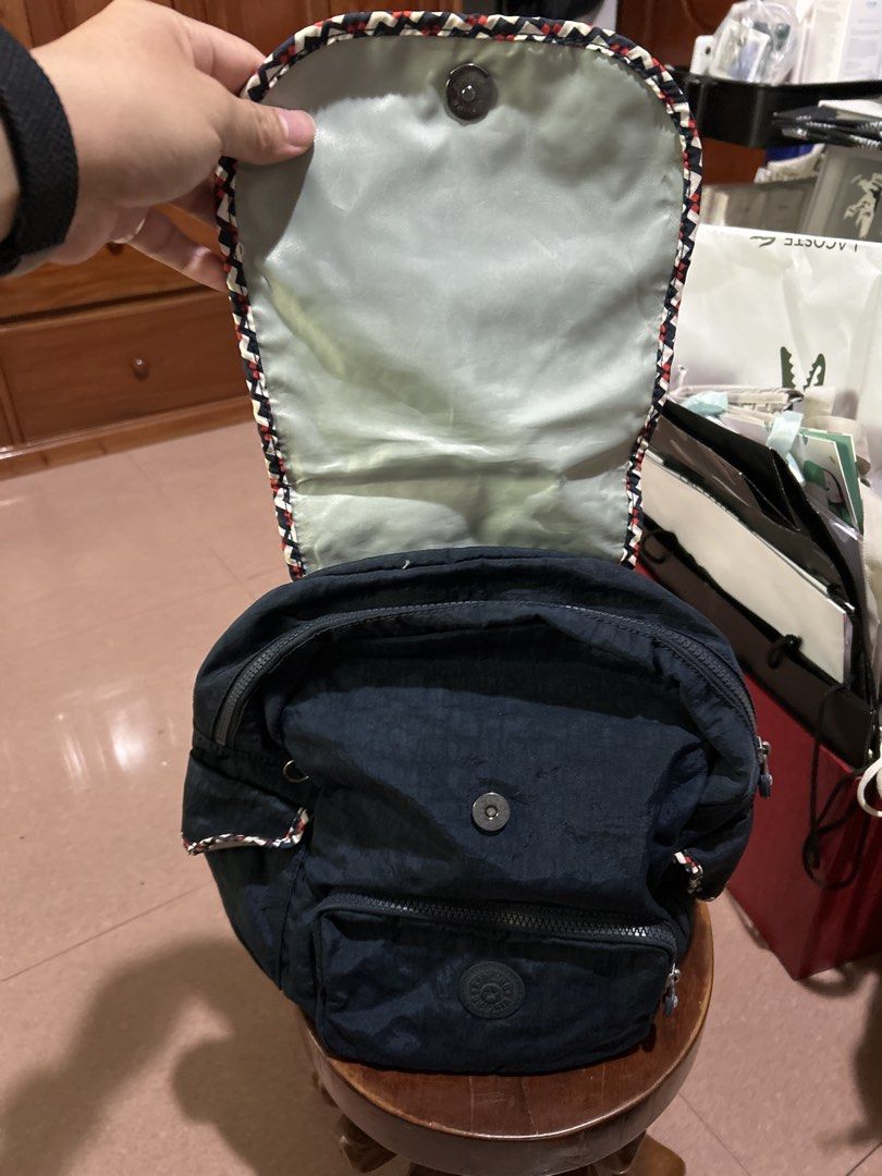 Kipling Navy Blue Backpack with Patterned Trim (Category: Backpacks) located in Alitagtag. Submitted by patrickvillanueva (Listing ID 1466623957, Image 3). Description: Navy blue nylon backpack from Kipling. Flap top with magnetic snap closure and patterned trim along the edge. Front zippered pocket with circular logo patch. Adjustable black straps on the back. Main compartment opens up with a zipper, revealing light-colored interior lining, slip