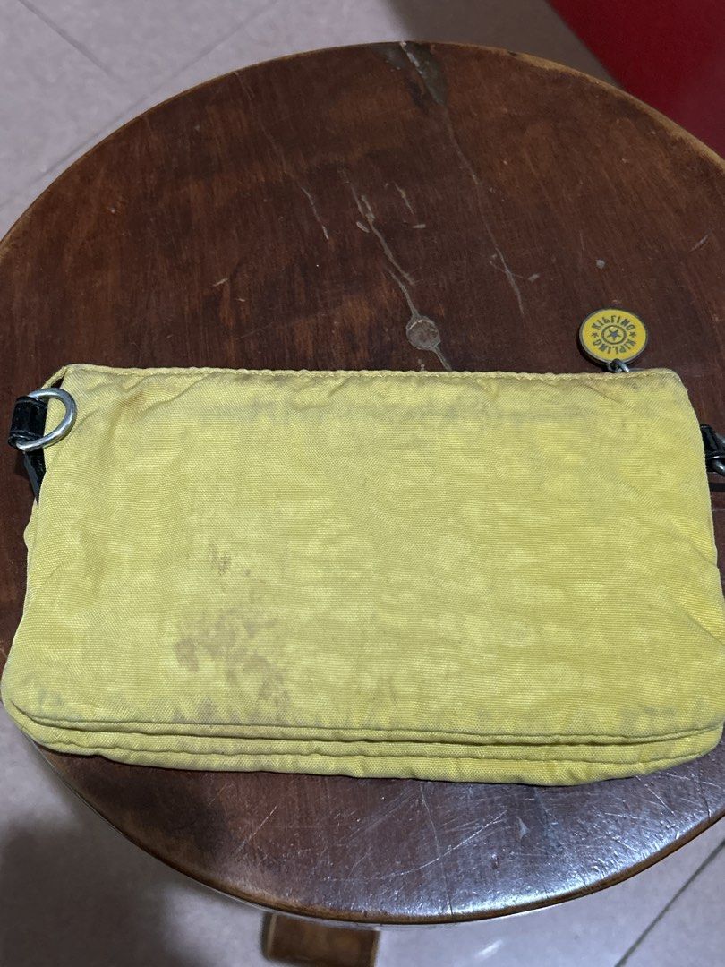 Kipling Yellow Clutch Wallet with Multiple Compartments (Category: Wallets & Card holders) located in Alitagtag. Submitted by patrickvillanueva (Listing ID 1466628886, Image 2). Description: - Brand: Kipling - Material: Signature crinkled nylon fabric - Color: Bright yellow - Exterior: Front flap pocket with dark trim and round Kipling logo zip pull - Interior: Multiple card slots, slip pockets, and a zippered coin compartment with grey leaf patt