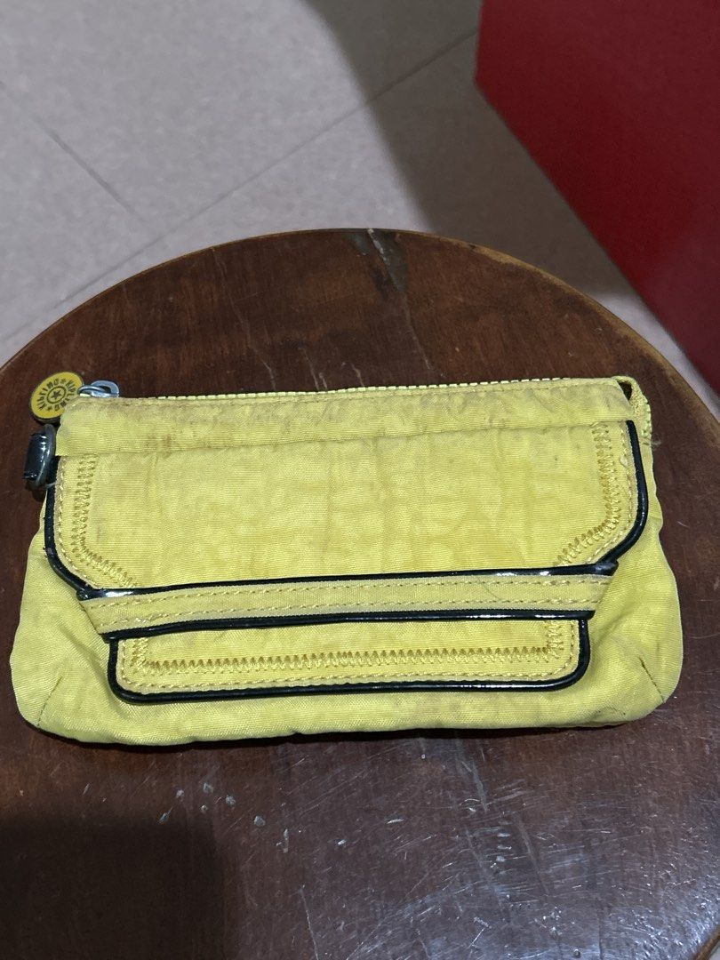 Kipling Yellow Clutch Wallet with Multiple Compartments (Category: Wallets & Card holders) located in Alitagtag. Submitted by patrickvillanueva (Listing ID 1466628886, Image 1). Description: - Brand: Kipling - Material: Signature crinkled nylon fabric - Color: Bright yellow - Exterior: Front flap pocket with dark trim and round Kipling logo zip pull - Interior: Multiple card slots, slip pockets, and a zippered coin compartment with grey leaf patt