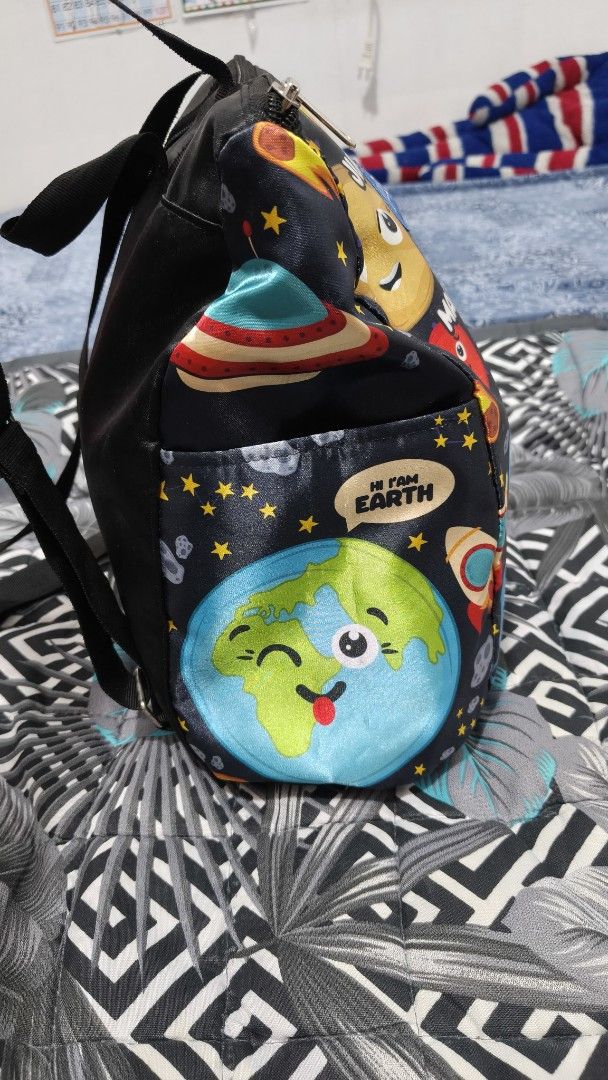 Kittly Space Print Kids Backpack with Solar System Design (Category: Backpacks) located in Manila. Submitted by phcarousince2016 (Listing ID 1466651338, Image 2). Description: - Brand: Kittly - Design: Fun outer space pattern with cartoon planets (Jupiter, Mars, Earth, Saturn), sun, and rockets on a dark background - Closure: Top zipper closure - Comfort: Adjustable black shoulder straps and a convenient grab handle - Storage: Handy exterior side