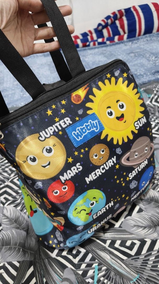 Kittly Space Print Kids Backpack with Solar System Design (Category: Backpacks) located in Manila. Submitted by phcarousince2016 (Listing ID 1466651338, Image 1). Description: - Brand: Kittly - Design: Fun outer space pattern with cartoon planets (Jupiter, Mars, Earth, Saturn), sun, and rockets on a dark background - Closure: Top zipper closure - Comfort: Adjustable black shoulder straps and a convenient grab handle - Storage: Handy exterior side