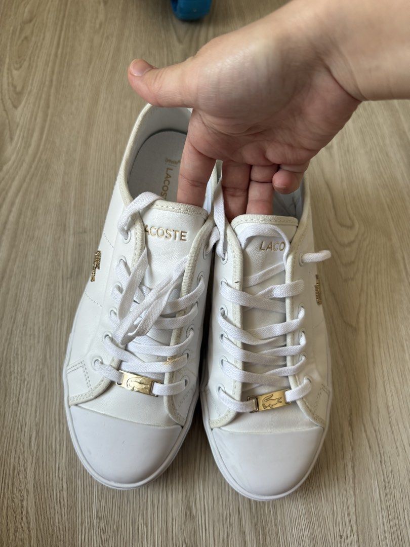 Lacoste White Leather Sneakers with Gold Hardware (Category: Sneakers) located in Rodriguez. Submitted by sheddmycloset (Listing ID 1466712363, Image 1). Description: - Authentic white leather Lacoste sneakers - Elegant gold hardware including eyelets and branded lace lock plates - Classic low-top design with durable rubber toe caps - Comfortable Ortholite insoles for all-day wear - Clean white laces and soles showing minimal signs of use.