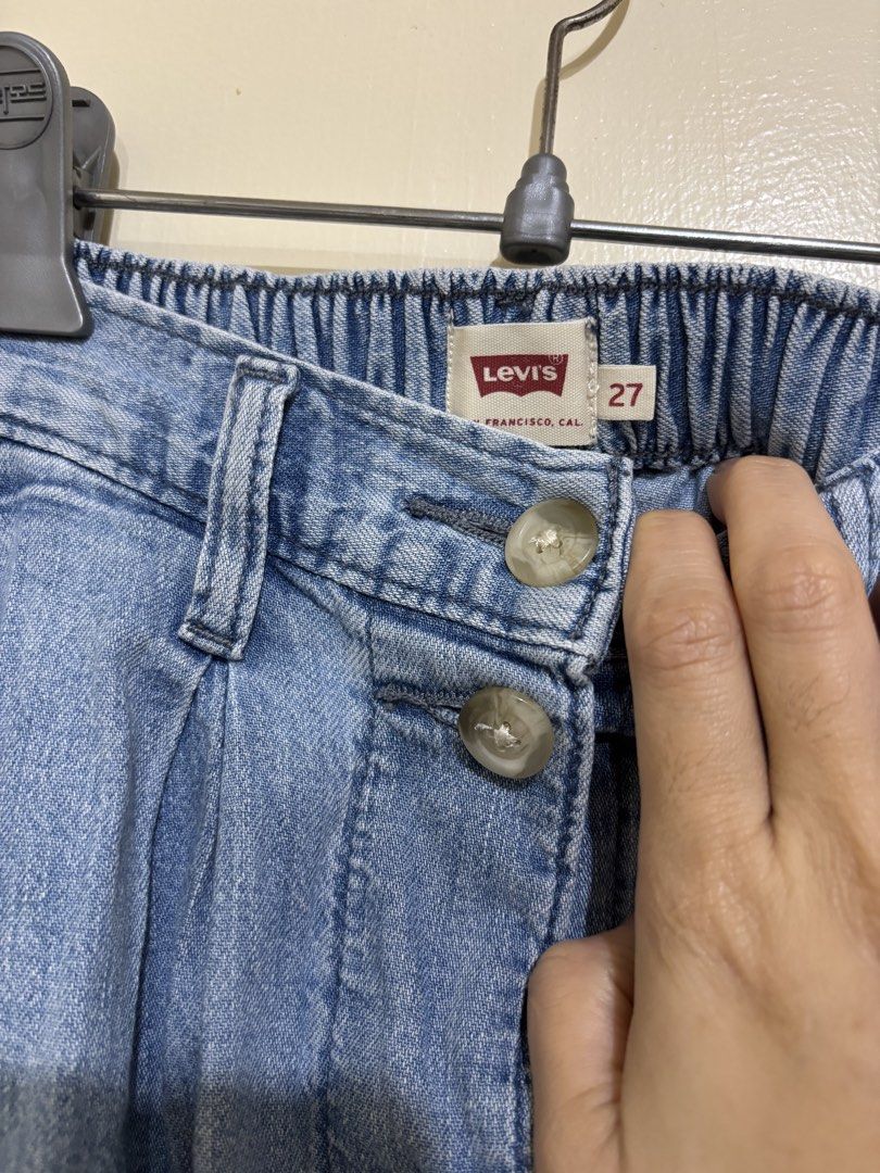 Levi's Denim Midi Skirt Size 27 (Category: Skirts) located in Balayan. Submitted by authenticfindsbymrb (Listing ID 1466701309, Image 2). Description: - Brand: Levi's - Style: Light wash denim midi skirt with front pleats - Closure: Front button-down with classic metal buttons - Waist: Partially elasticized at the back for extra comfort - Size: 27 (tag attached) - Condition: Great casual piece, easy to pair with tees and sweaters.