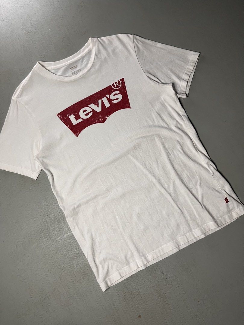 Levi's White Graphic Tee Size S (Category: Shirts) located in Catbalogan. Submitted by yellfindss (Listing ID 1466745451, Image 3). Description: White Levi's crew neck t-shirt with distressed red batwing logo print across the chest. Short sleeves, standard fit. Made in Sri Lanka. Small red Levi's tab on the lower left seam. Tag printed inside the collar shows size S. Clean fabric, minimal signs of wear. -18/26.