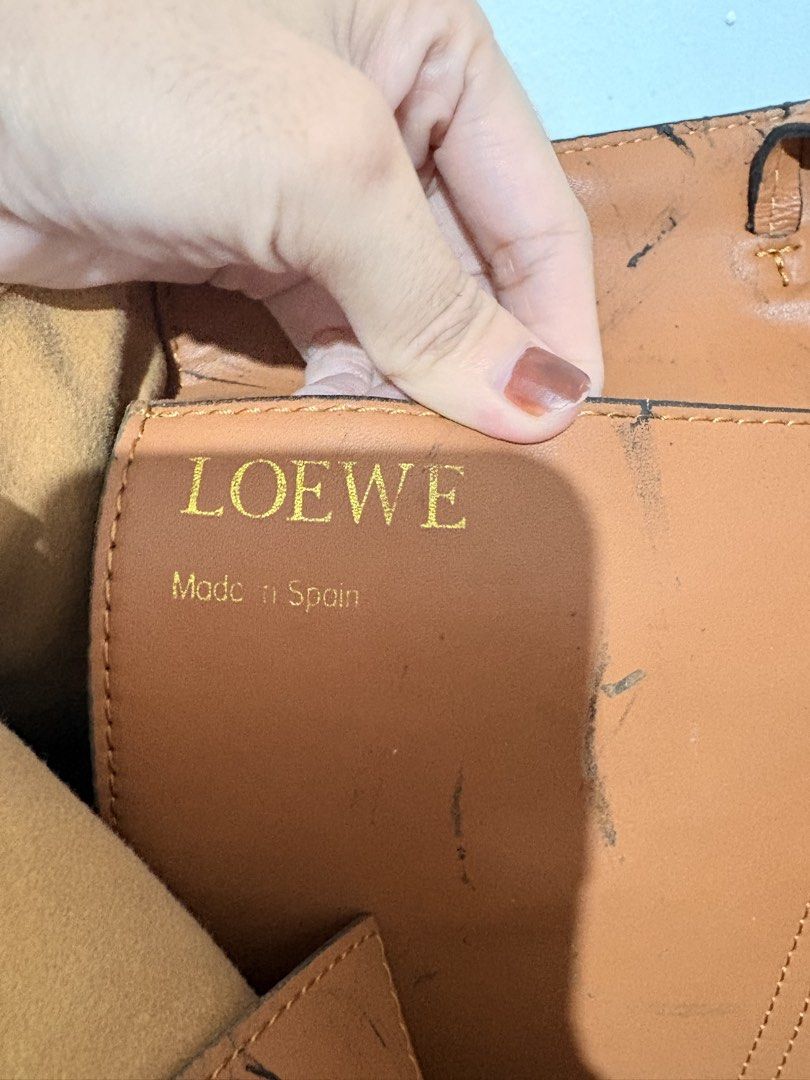 Loewe Brown Leather Tote Bag (Category: Tote Bags) located in Manila. Submitted by jama_20 (Listing ID 1466654462, Image 3). Description: - Brand: Loewe - Origin: Made in Spain - Material: Premium brown leather - Design: Structured handles with intricate woven detail and embossed front logo - Interior: Spacious main compartment with matching pouch pocket featuring gold foil branding - Condition: Pre-loved with visible dark scratches and marks on 
