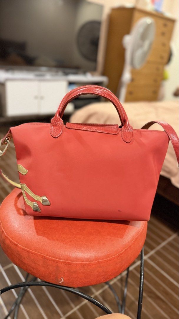 Longchamp Le Pliage Red Tote Bag with Strap (Category: Luxury Bags & Wallets) located in San Fernando. Submitted by jusaki17 (Listing ID 1466703053, Image 2). Description: - Brand: Longchamp - Color: Red with leather trim and gold-tone hardware - Material: Durable nylon - Features: Top handles, detachable shoulder strap, zip-top closure with snap flap, and iconic gold horse appliqué - Interior: Roomy main compartment with matching printed fabric 