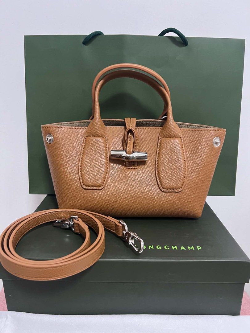 Longchamp Roseau Top Handle Bag (Category: Luxury Bags & Wallets) located in Abulug. Submitted by jamiecammie (Listing ID 1466701205, Image 1). Description: - Authentic Tan Leather Longchamp Roseau Bag - Structured design with signature silver-tone bamboo toggle closure - Includes matching detachable shoulder strap and top handles - Interior features zippered pocket with racing horse logo plaque - Comes complete with original green box and paper 