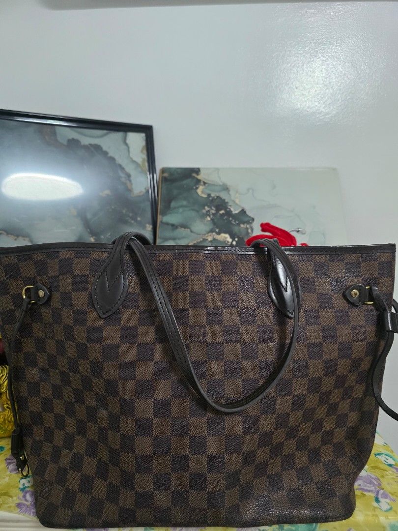 Louis Vuitton Damier Ebene Neverfull Tote Bag (Category: Luxury Bags & Wallets) located in Binan City. Submitted by geraldinef58404 (Listing ID 1466617874, Image 1). Description: Louis Vuitton Neverfull tote bag in the classic Damier Ebene canvas print. Brown and dark brown checkered pattern with dark brown leather shoulder straps and side cinch laces. Gold-tone hardware throughout. Red interior lining inside. Roomy everyday shoulder bag with sli