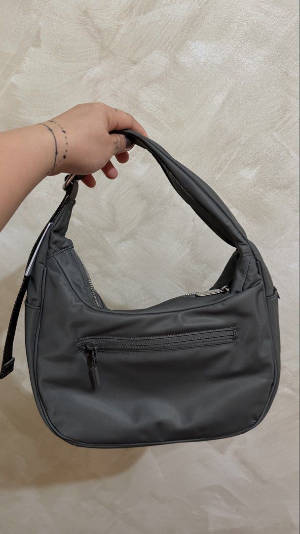 Lululemon Curved Lines Shoulder Bag (Category: Shoulder Bags) located in Las Pinas. Submitted by mharjrahm (Listing ID 1466619765, Image 2). Description: - Brand: Lululemon - Style: Crescent shoulder bag in grey - Material: Smooth nylon with metal hardware and front logo emblem - Compartments: Main zip top closure and exterior zippered back pocket - Strap: Adjustable shoulder strap - Condition: Brand new, clean inside and out, tags still attached