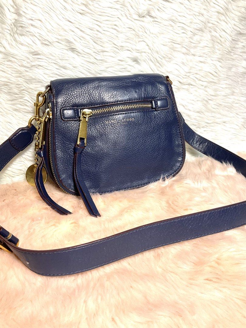 Marc Jacobs Navy Blue Leather Crossbody Bag (Category: Cross-body Bags) located in La Trinidad. Submitted by naravincollections (Listing ID 1466651337, Image 1). Description: Dark blue pebbled leather Marc Jacobs crossbody bag with gold hardware. Zippered pocket on the front flap plus another pocket on the back. Adjustable and detachable shoulder strap with metal clips. Fabric lining inside with magnetic closure. Leather zipper pulls and metal lo