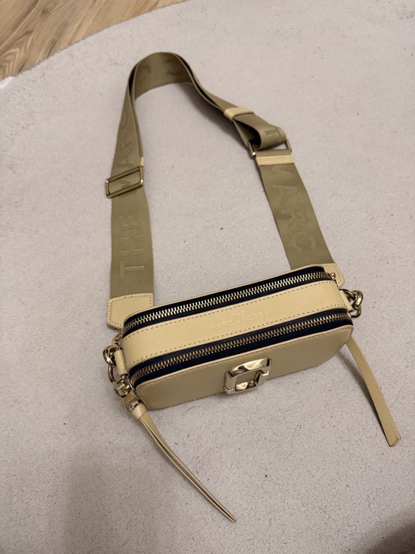 Marc Jacobs The Snapshot Camera Bag Cream Gold (Category: Luxury Bags & Wallets) located in Manila. Submitted by jolynfarah66339 (Listing ID 1466630794, Image 2). Description: - Authentic Marc Jacobs Snapshot camera bag in cream - Sleek smooth leather finish with luxurious gold hardware - Dual zip compartments for easy organization - Wide khaki logo webbing strap for comfortable wear - Comes with original paper brand card tag - Compact, stylish, 