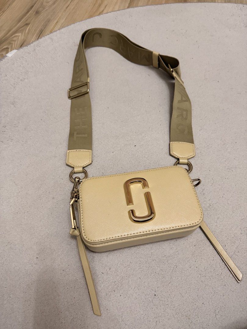 Marc Jacobs The Snapshot Camera Bag Cream Gold (Category: Luxury Bags & Wallets) located in Manila. Submitted by jolynfarah66339 (Listing ID 1466630794, Image 1). Description: - Authentic Marc Jacobs Snapshot camera bag in cream - Sleek smooth leather finish with luxurious gold hardware - Dual zip compartments for easy organization - Wide khaki logo webbing strap for comfortable wear - Comes with original paper brand card tag - Compact, stylish, 