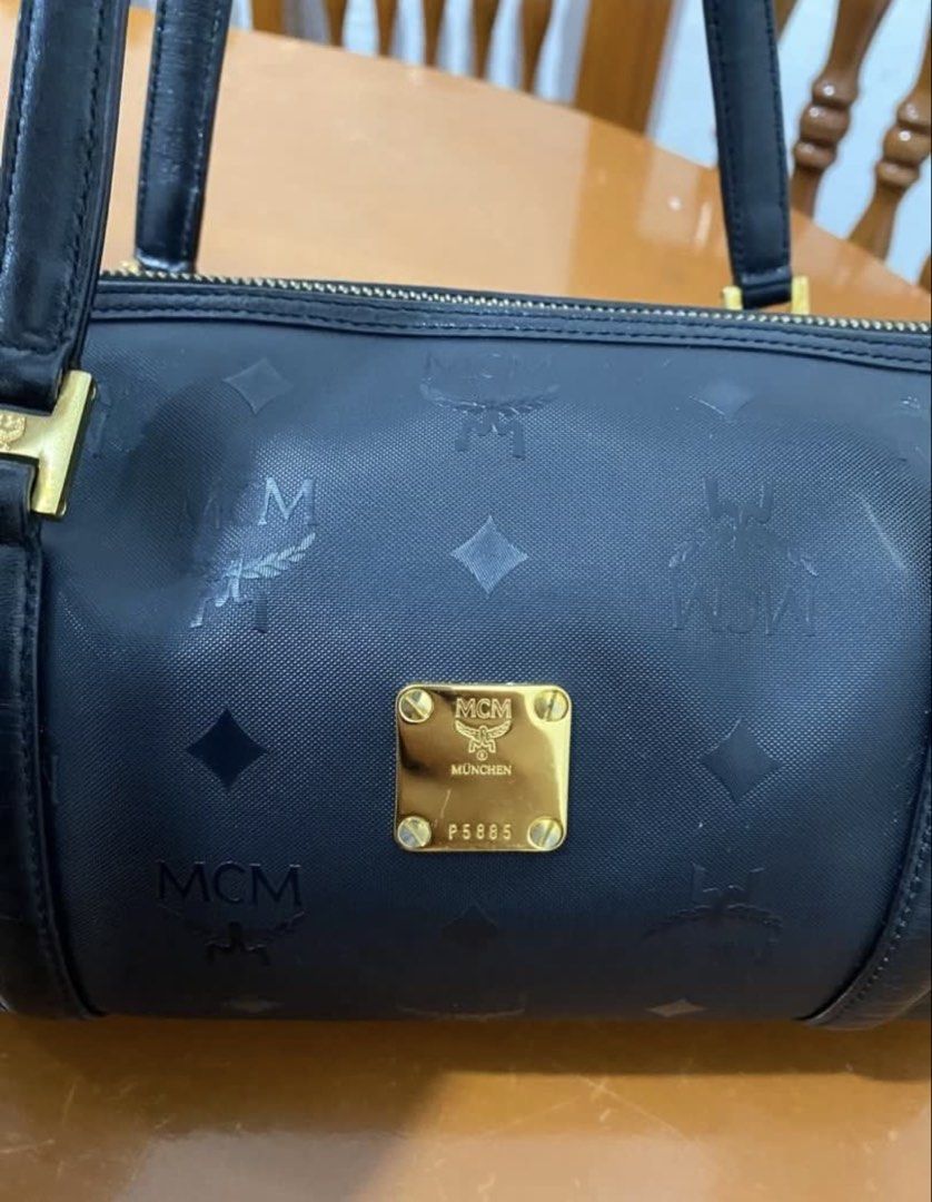 MCM Black Monogram Barrel Handbag (Category: Luxury Bags & Wallets) located in Naga. Submitted by cozydapper (Listing ID 1466628451, Image 3). Description: - Authentic MCM black barrel bag with iconic monogram print - Elegant gold-tone hardware featuring the München plaque and code P5885 - Comfortable dual shoulder straps with square gold loop attachments - Secure top-zip closure - Clean exterior and hardware overall.