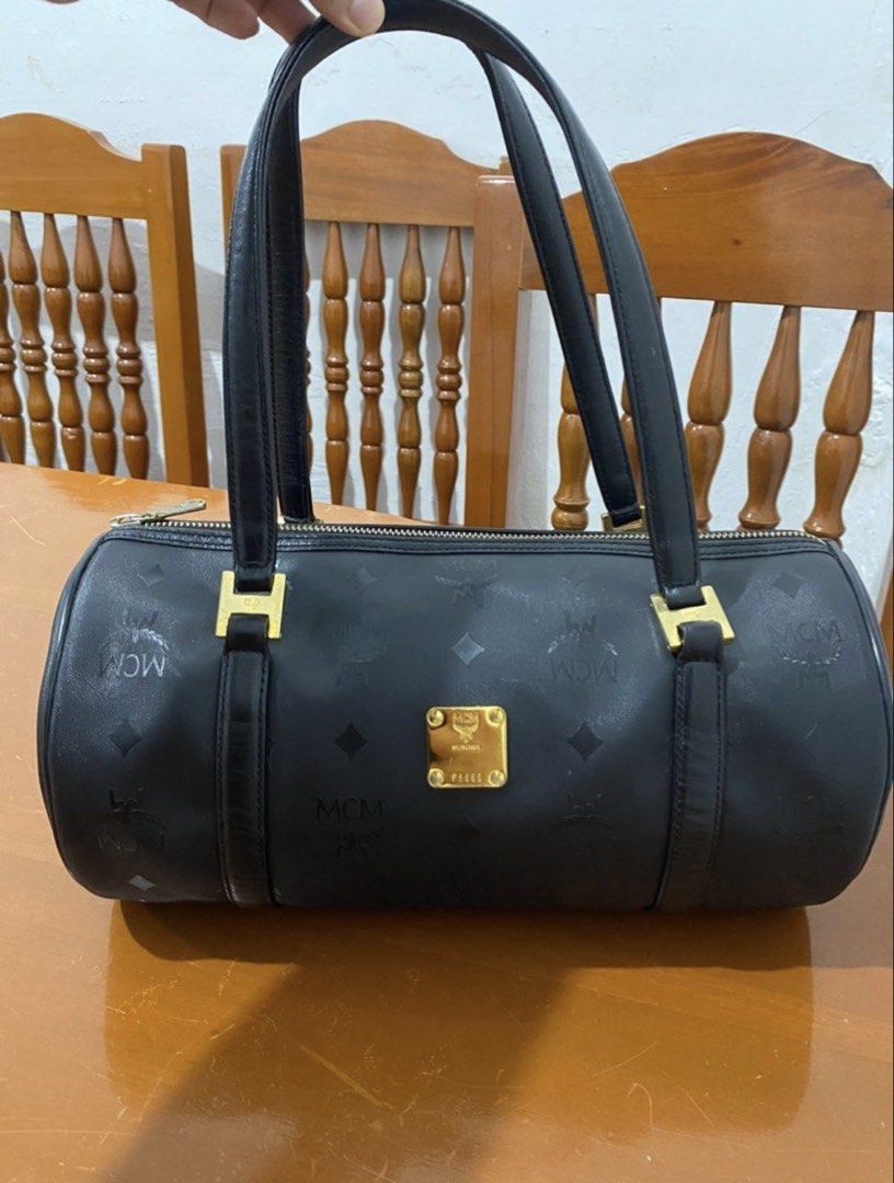 MCM Black Monogram Barrel Handbag (Category: Luxury Bags & Wallets) located in Naga. Submitted by cozydapper (Listing ID 1466628451, Image 1). Description: - Authentic MCM black barrel bag with iconic monogram print - Elegant gold-tone hardware featuring the München plaque and code P5885 - Comfortable dual shoulder straps with square gold loop attachments - Secure top-zip closure - Clean exterior and hardware overall.