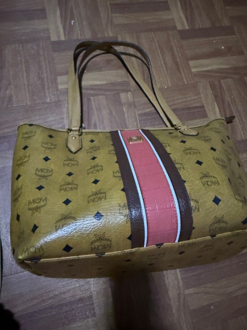 MCM Monogram Tote Bag with Center Stripe (Category: Luxury Bags & Wallets) located in Quezon City. Submitted by prelovedco (Listing ID 1466679845, Image 1). Description: - Brand: MCM Monogram Tote Bag - Color: Classic cognac yellow with a bold brown and pink vertical center stripe - Material: Clean coated canvas with all-over monogram print - Hardware: Premium gold-tone hardware - Straps: Comfortable dual shoulder straps - Compartments: Large ope