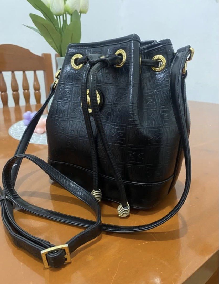 Metrocity Black Monogram Bucket Bag with Gold Hardware (Category: Luxury Bags & Wallets) located in Naga. Submitted by cozydapper (Listing ID 1466629428, Image 2). Description: - Brand: Metrocity - Color: Classic Black - Pattern: All-over embossed monogram - Closure: Secure drawstring with gold-tone metal eyelets - Details: Front logo emblem and gold hardware hooks - Strap: Adjustable long shoulder strap - Interior: Fabric lining with a zip pocke