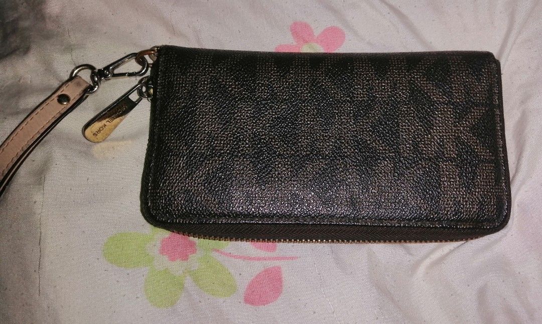 Michael Kors Brown Monogram Zip Around Wristlet Wallet (Category: Wallets & Card holders) located in Quezon City. Submitted by rolenalma (Listing ID 1466609046, Image 3). Description: Michael Kors zip-around wallet in dark brown monogram print. Includes a detachable light beige wrist strap and gold-tone hardware with an engraved plaque on the front. Interior features multiple card slots, a central zipped compartment for coins, and slip pockets fo