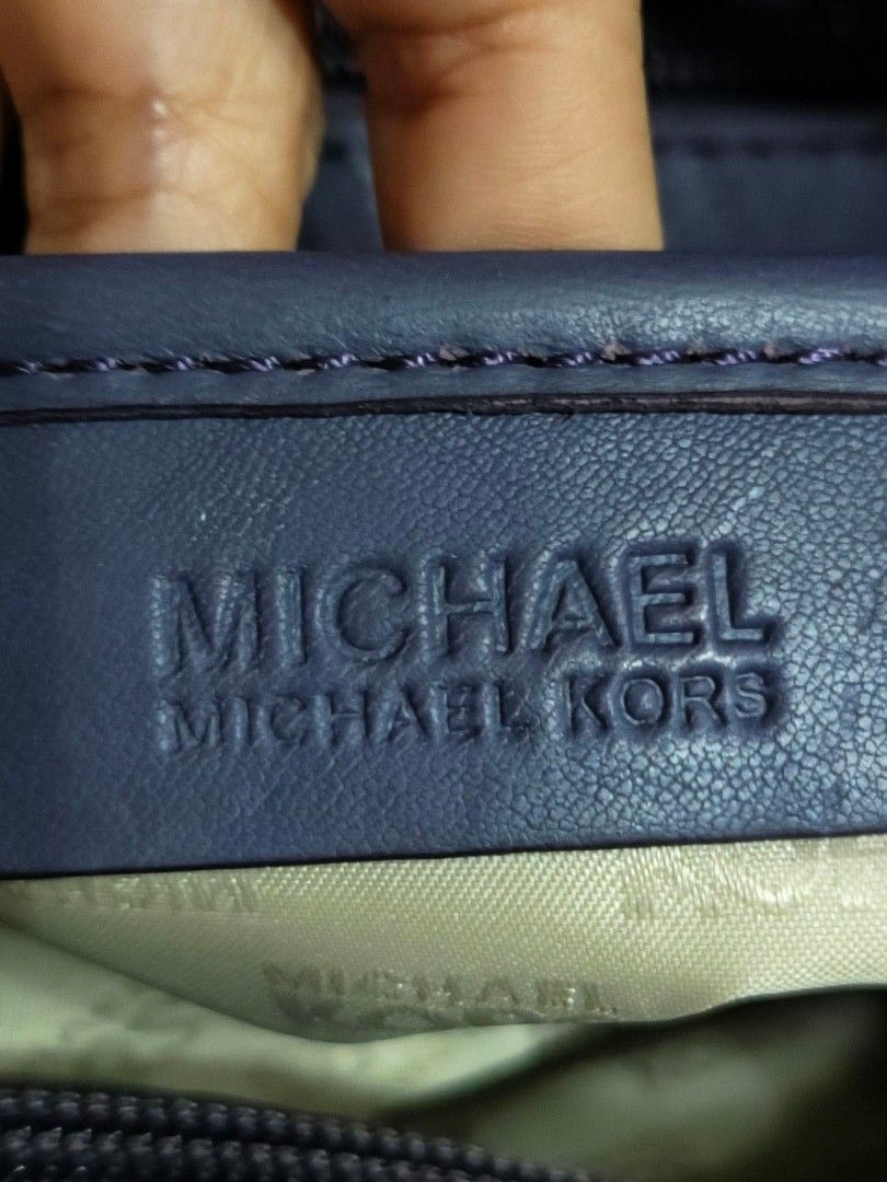 Michael Kors Purple Leather Shoulder Bag (Category: Luxury Bags & Wallets) located in Cavite. Submitted by mahthriftshop (Listing ID 1466573325, Image 3). Description: Michael Kors leather shoulder bag in a deep purple shade. Features gold-tone hardware, a drawstring closure with a toggle, and sturdy double handles attached via rings. Interior lined with signature fabric and includes an embossed brand patch along with a Made in China tag..