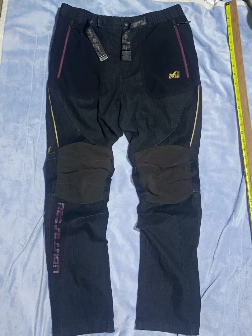 Millet Mountain By Experience Hiking Pants (Category: Trousers) located in City of Isabela. Submitted by warmbird.d06e6f (Listing ID 1466670621, Image 1). Description: - Brand: Millet Mountain by Experience - Color: Black with pinkish-red pocket trim and gold logo embroidery - Material: Durable textured fabric - Features: Built-in patterned belt with buckle, zippered side pockets, and reinforced knee patches - Best for: Trekking, climbing, campin