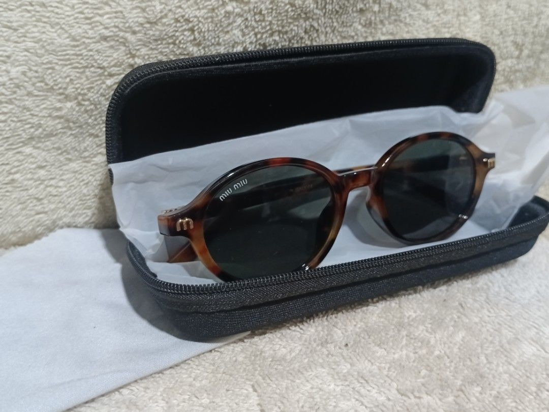 Miu Miu Tortoiseshell Round Sunglasses (Category: Sunglasses & Eyewear) located in Cavite. Submitted by navias (Listing ID 1466644104, Image 2). Description: - Brand: Miu Miu - Style: Round sunglasses with tortoiseshell frame and gold metal details - Lenses: Dark green with 'M' logo on the temples - Condition: Excellent, zero scratches on lenses, clean frames - Model & Size: 5523, 50-20-141 - Origin: Made in Italy - Inclusions: Black zippered har