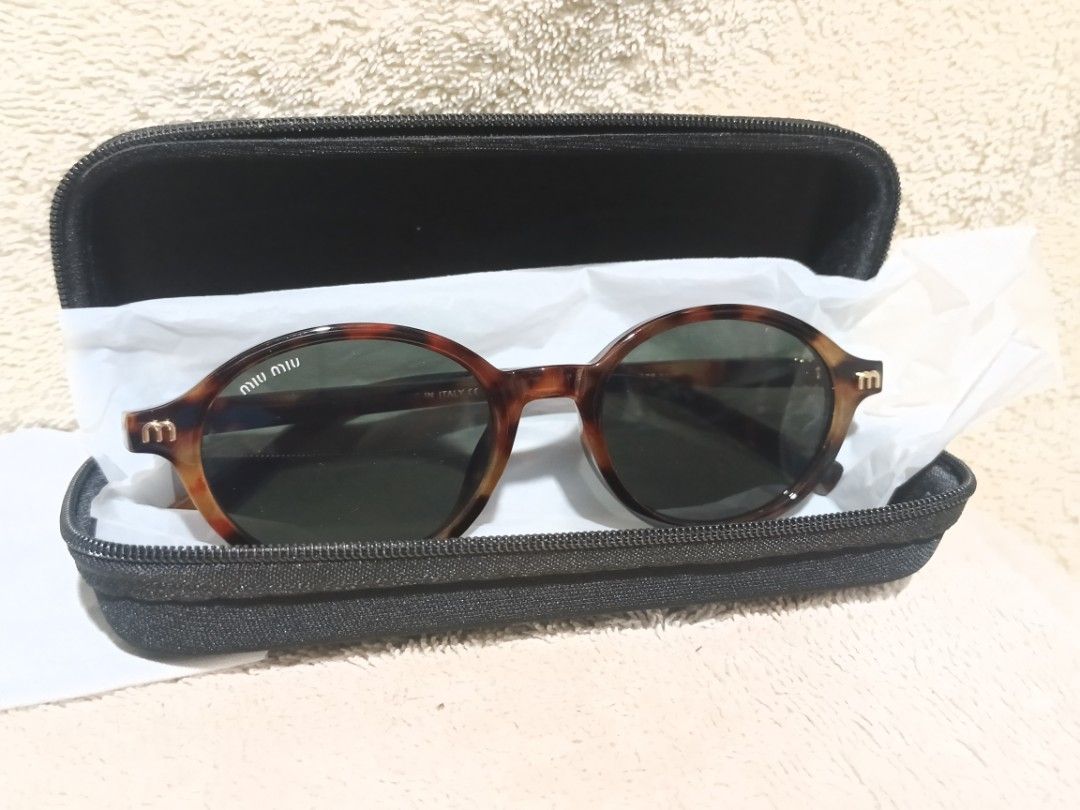 Miu Miu Tortoiseshell Round Sunglasses (Category: Sunglasses & Eyewear) located in Cavite. Submitted by navias (Listing ID 1466644104, Image 1). Description: - Brand: Miu Miu - Style: Round sunglasses with tortoiseshell frame and gold metal details - Lenses: Dark green with 'M' logo on the temples - Condition: Excellent, zero scratches on lenses, clean frames - Model & Size: 5523, 50-20-141 - Origin: Made in Italy - Inclusions: Black zippered har