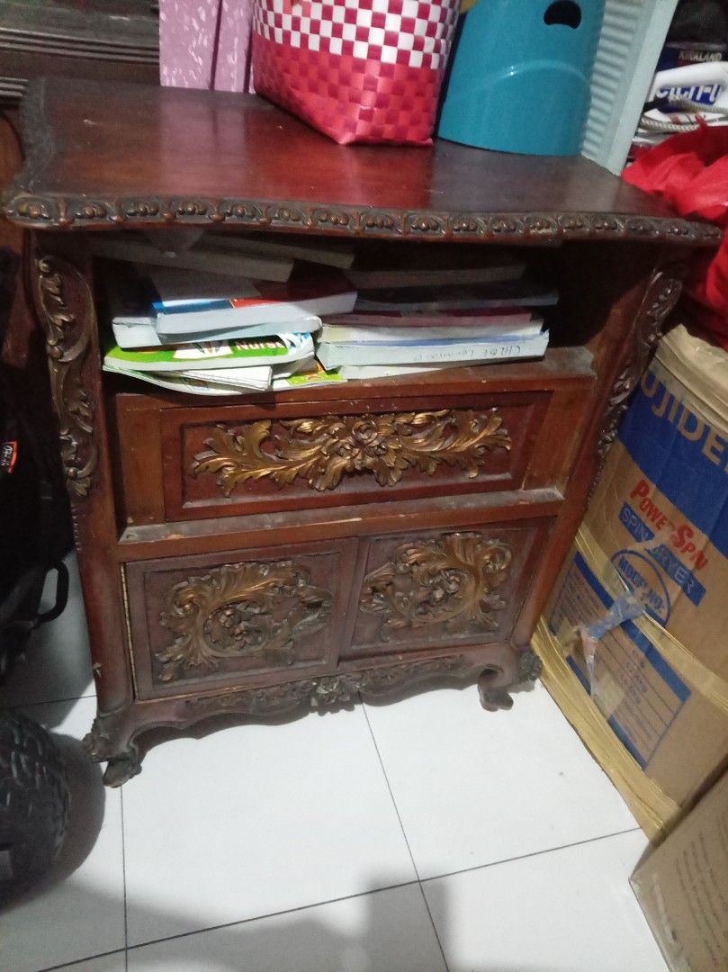 Narra for sale (Category: Shelves, Cabinets & Racks) located in Caloocan City. Submitted by maynaito (Listing ID 1466683270, Image 1). Description: - Style: Classic traditional design in rich dark wood with gold-toned carving accents - Storage: 1 pull-out drawer, lower cabinet with doors, and a handy open shelf for books - Design details: Ornate carved floral motifs, elegant scalloped top edge, and graceful cabriole legs - Condition: Solid and st
