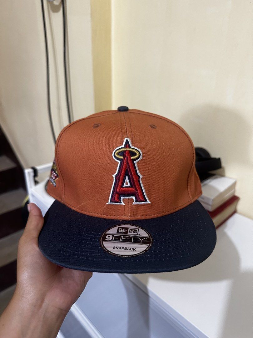 New Era 9Fifty Anaheim Angels Snapback Hat (Category: Caps & Hats) located in Baler. Submitted by sidequester (Listing ID 1466583797, Image 1). Description: - Team: Anaheim Angels (Cooperstown Collection - 2002 World Champions 20th Anniversary Edition) - Design: Orange crown, dark blue flat brim, and red undervisor - Fit: Classic snapback closure (Adjustable) - Details: Commemorative side patch on the right, original sticker still attached to the