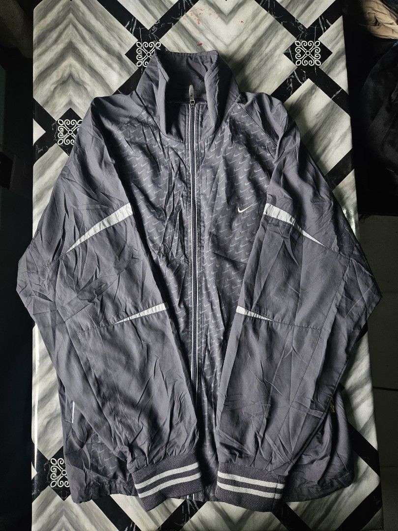 Nike ACG Grey Full Zip Windbreaker Track Jacket (Category: Coats, Jackets and Outerwear) located in Manila. Submitted by shanshan.river (Listing ID 1466593430, Image 3). Description: - Color: Grey - Brand: Nike ACG - Design: All-over subtle mini swoosh pattern - Closure: Full front zipper with standing collar - Details: Striped ribbed cuffs and hem, small ACG mountain logo and Nike lettering on the back, yellow and black woven sleeve tag - Materi