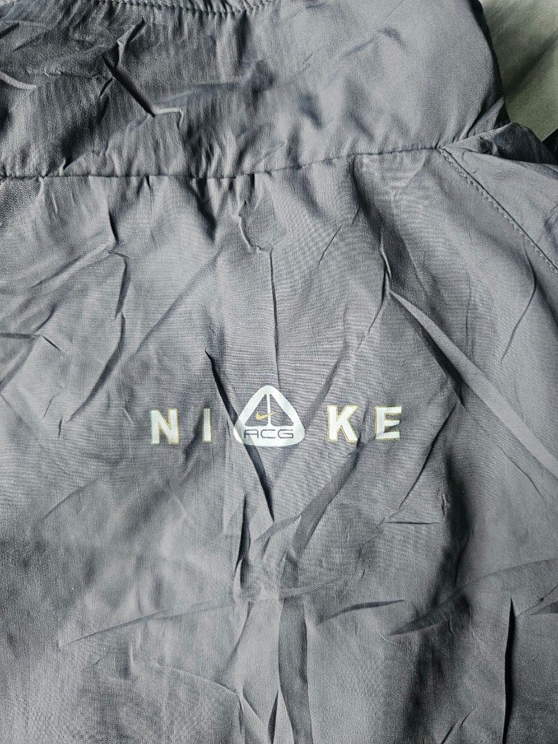 Nike ACG Grey Full Zip Windbreaker Track Jacket (Category: Coats, Jackets and Outerwear) located in Manila. Submitted by shanshan.river (Listing ID 1466593430, Image 1). Description: - Color: Grey - Brand: Nike ACG - Design: All-over subtle mini swoosh pattern - Closure: Full front zipper with standing collar - Details: Striped ribbed cuffs and hem, small ACG mountain logo and Nike lettering on the back, yellow and black woven sleeve tag - Materi