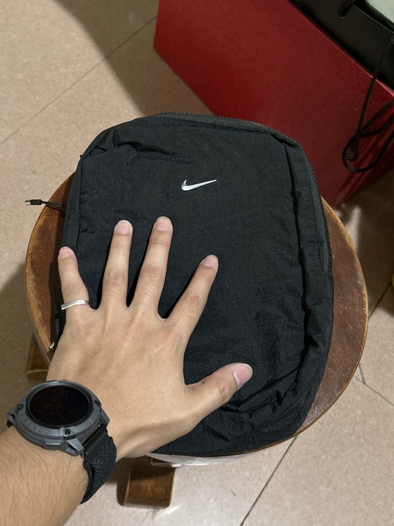 Nike Aura Cross-Body Bag (5L) (Category: Sling Bags) located in Alitagtag. Submitted by patrickvillanueva (Listing ID 1466618385, Image 2). Description: The Nike Aura Cross-Body Bag (5L) - Color: Classic Black - Material: Durable, high-quality nylon - Branding: Small white Nike Swoosh on front flap pocket - Strap: Adjustable black strap with sturdy buckle closure - Compartments: Wide-opening main compartment with internal mesh zip pocket - Extras