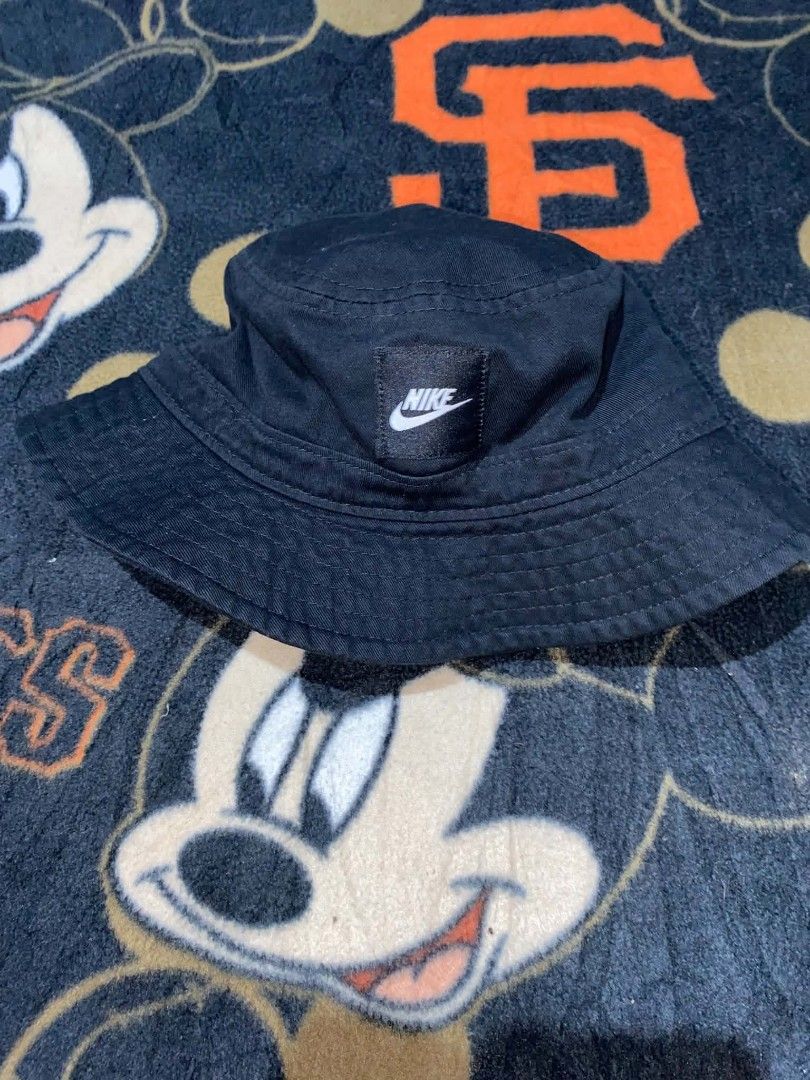 Nike Black Bucket Hat Size S/M (Category: Caps & Hats) located in Cebu City. Submitted by xyvielzyre (Listing ID 1466689762, Image 2). Description: Nike black bucket hat. Classic design with stitched brim and structured crown. Prominent Nike logo patch sewn on the front panel. Interior tag shows size S/M with Nike Swoosh branding. Lightweight cotton fabric, breathable construction. Ready to wear for casual outings or sunny days..